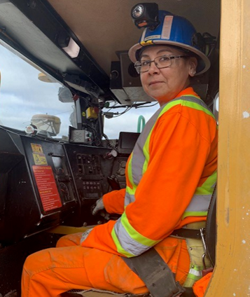 Woman with safety equipment operating mining equipment